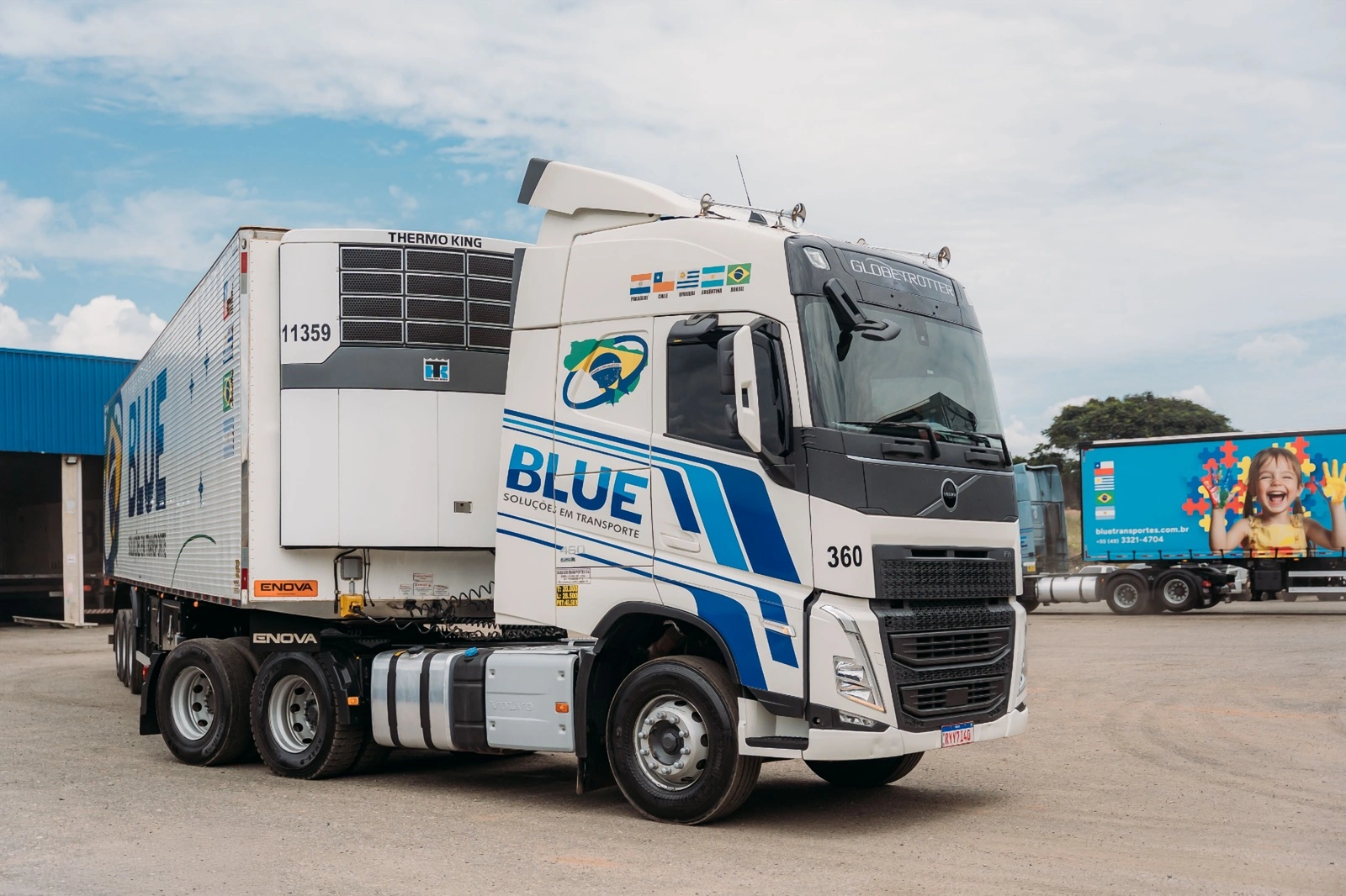 Cavalo Volvo número 360 da BLUE, branco com faixas azuis, engatado a uma carreta frigorífica com equipamento de refrigeração Thermo King.