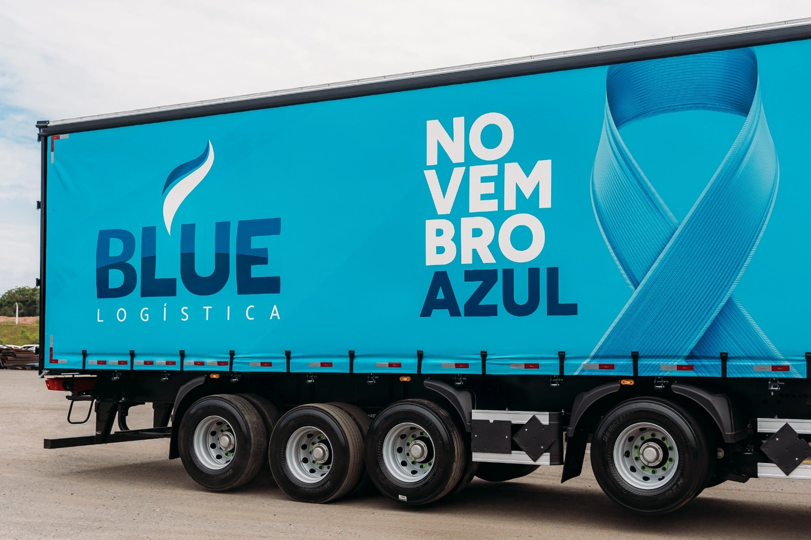Lona da carreta Novembro Azul com a marca BLUE Logística e o laço azul.